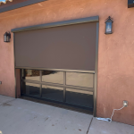 This Bronze Motorized Garage Screen Door, you can see the cord plugged in to the wall as the installer is testing it. Rolls up and down.