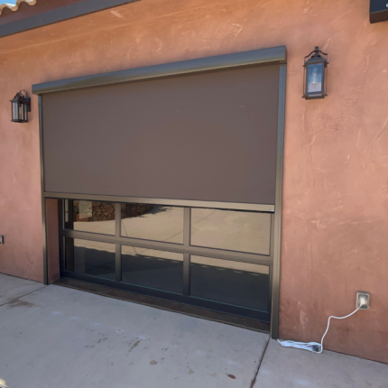This Bronze Motorized Garage Screen Door, you can see the cord plugged in to the wall as the installer is testing it. Rolls up and down.